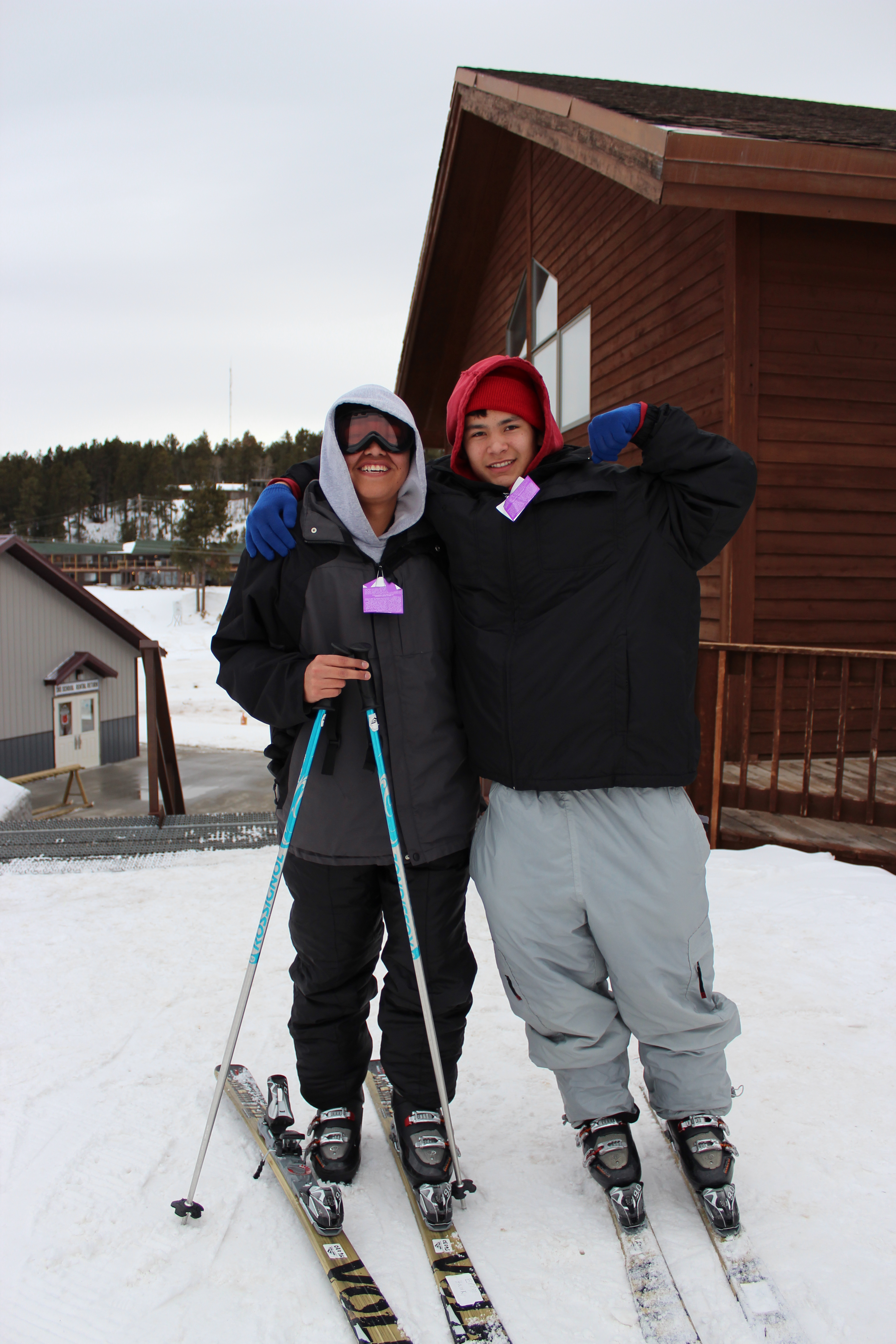 Two boys posing for a picture while on the slopes.