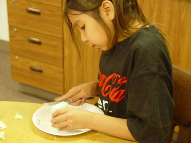 Kara is carving her soap into a Native American pipe.