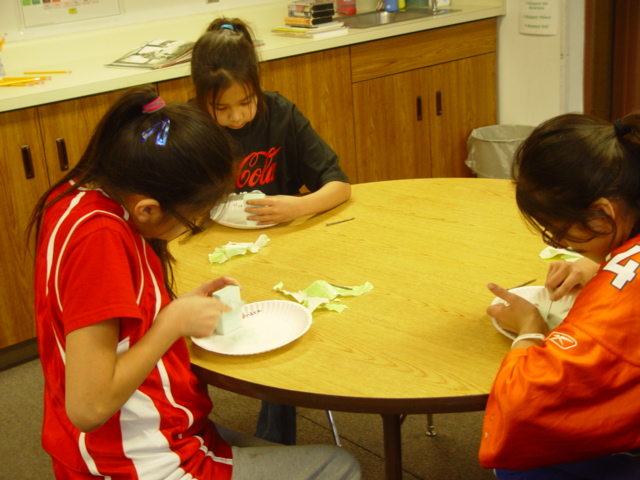 Three Native American students carving pipes