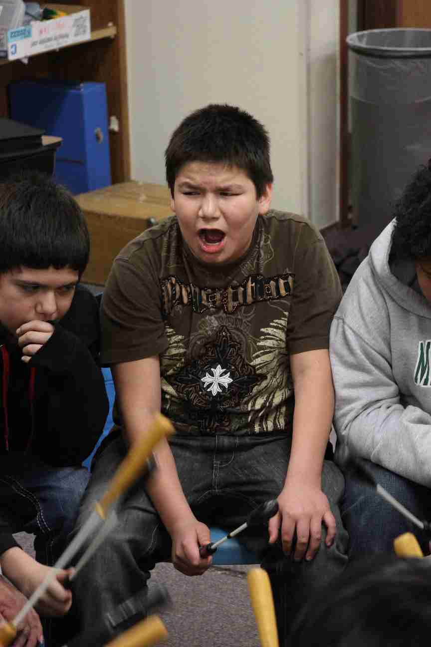 Lakota boy singing while playing the drum. 