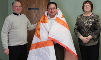 St. Joseph’s Indian School presents a Lakota star quilt in appreciation for Fr. Jack’s time on the board. 