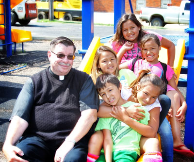 Fr. Anthony takes a break on the playground with the Lakota children. 