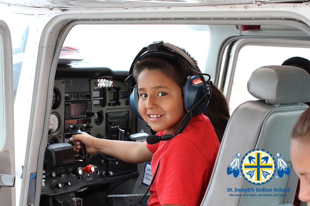 Young boy sits in cockpit of plane. 