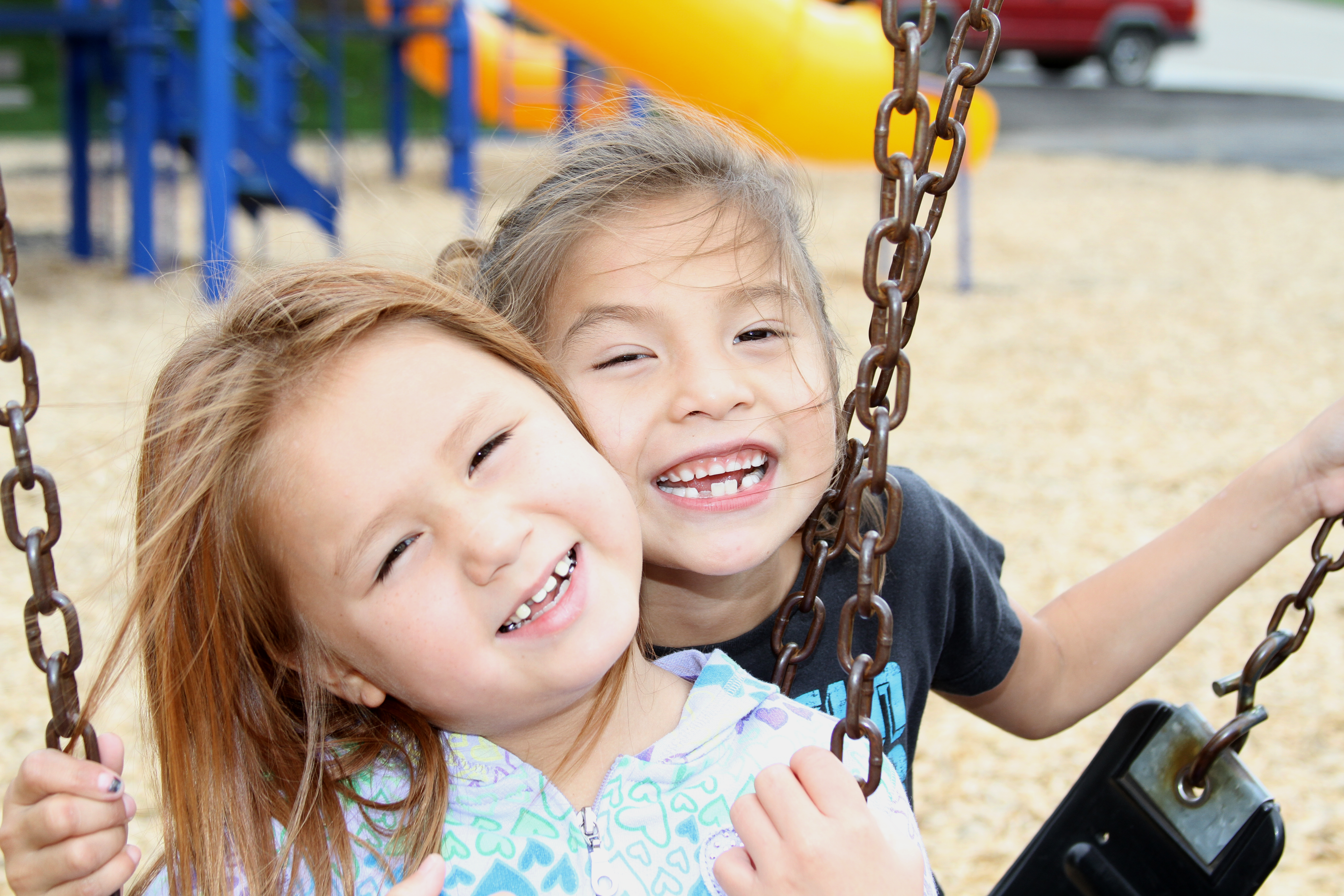 Two young girls play on the playground