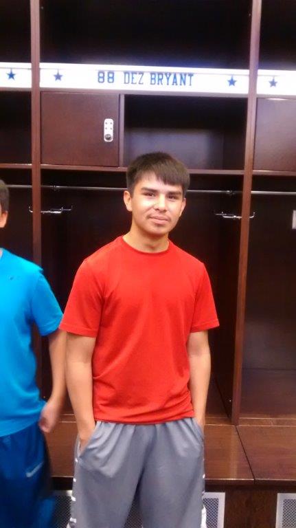 A student stands in front of a Cowboy player's locker.  