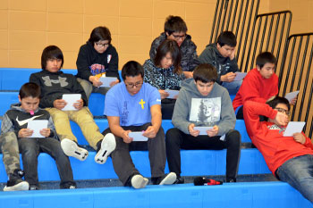 A group of St. Joseph’s junior high boys are pictured sitting on the bleachers. Their eyes are glued to their bingo cards. 